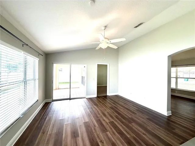 a view of an empty room with a window and wooden floor