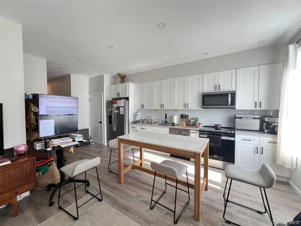 a kitchen with stainless steel appliances kitchen island granite countertop a table chairs microwave and sink