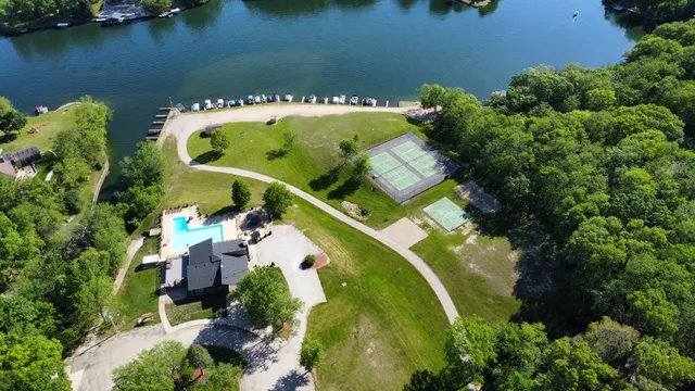 an aerial view of a residential houses with outdoor space and trees all around