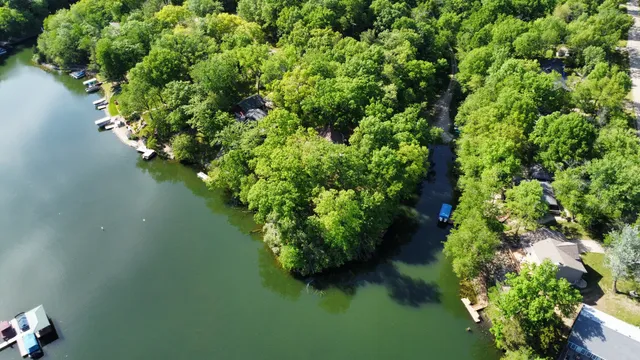 an aerial view of lake residential house with outdoor space and trees all around