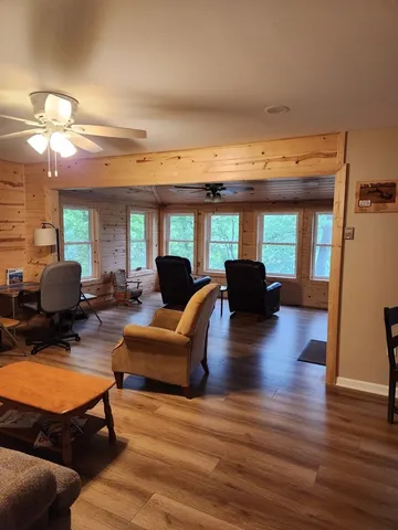 a living room with furniture a lamp wooden floor and a large window