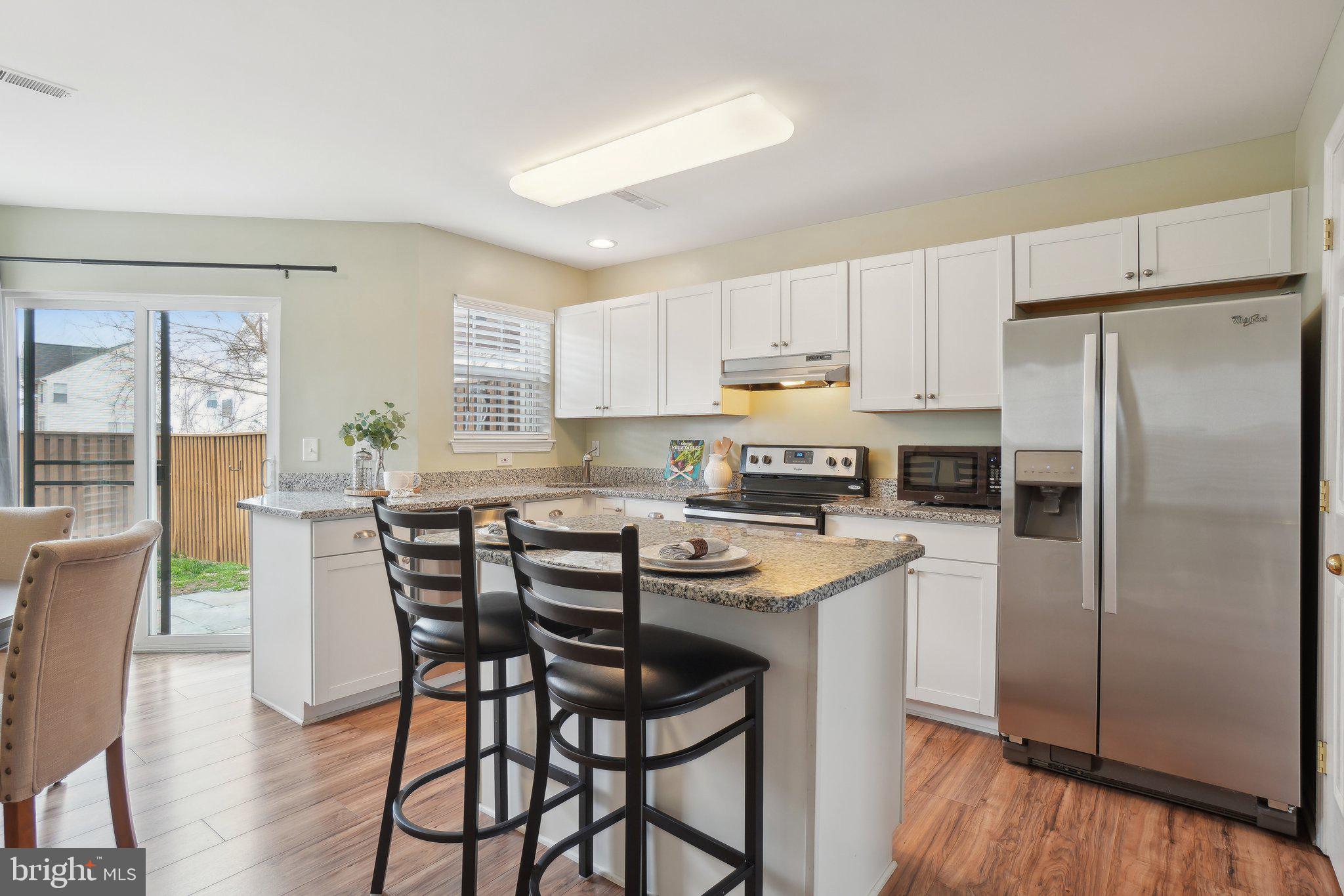 25379 Bryson Drive Chantilly, VA 20152 - Photo 5 of 28 a kitchen with kitchen island a refrigerator a stove a dining table and chairs