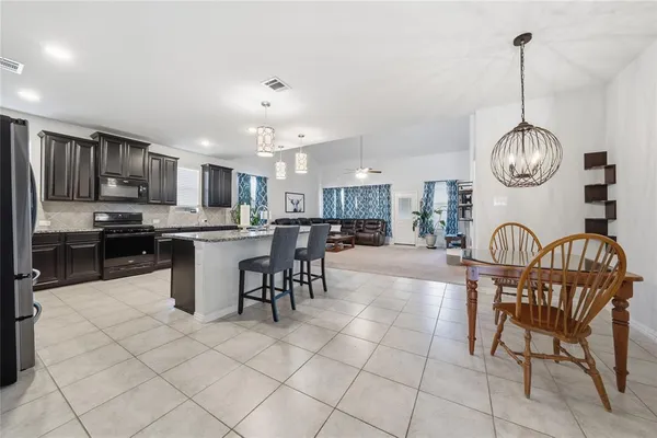 a kitchen with kitchen island granite countertop a stove a sink a dining table and chairs with wooden floor