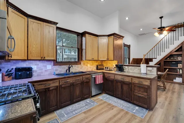 a kitchen with stainless steel appliances granite countertop a stove top oven a sink dishwasher a microwave oven and a refrigerator with wooden floor