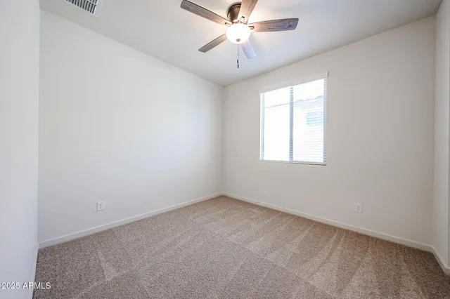 an empty room with a window and a fan