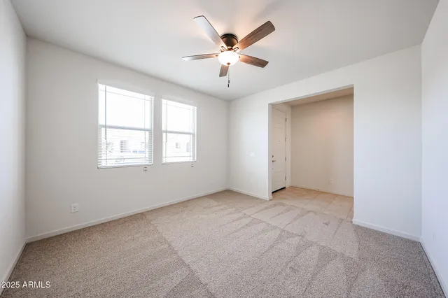 an empty room with ceiling fan and windows