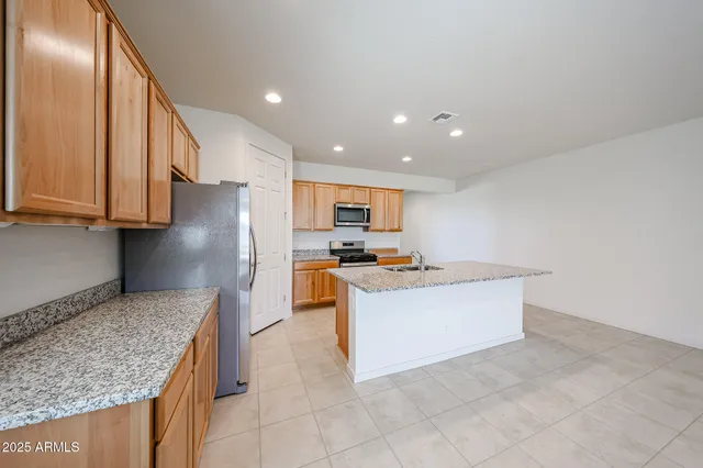 a kitchen with stainless steel appliances granite countertop a stove top oven a sink a refrigerator and white cabinets