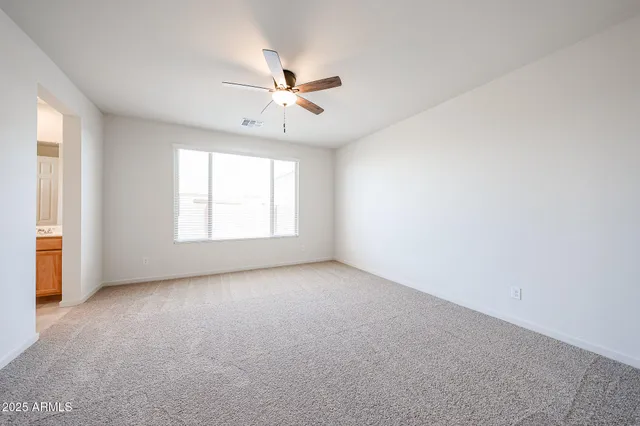 an empty room with windows and fan