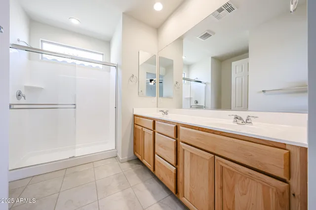 a bathroom with a double vanity sink a mirror and a shower
