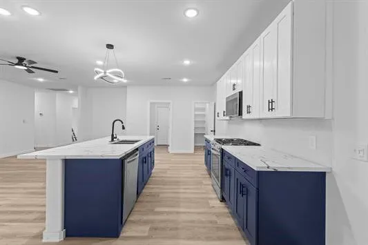a large white kitchen with stainless steel appliances granite countertop a stove and a sink