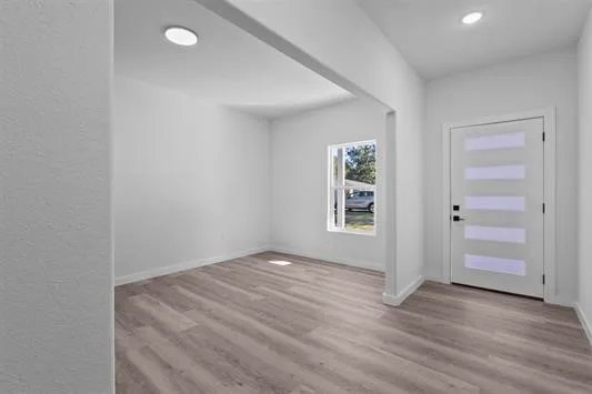 a view of an empty room with wooden floor and a window