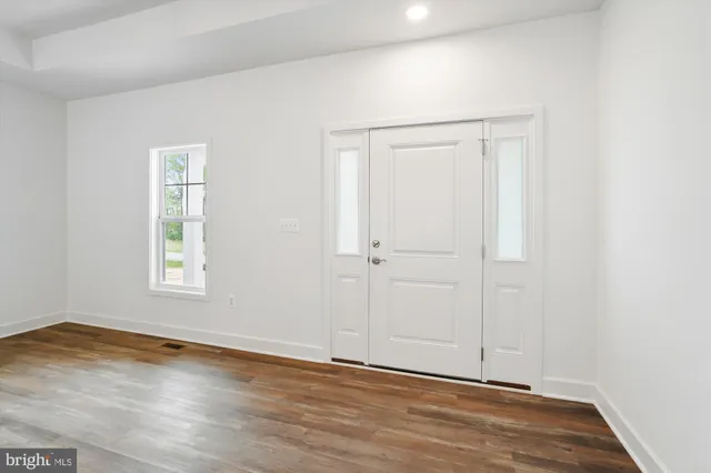an empty room with wooden floor ceiling fan and windows