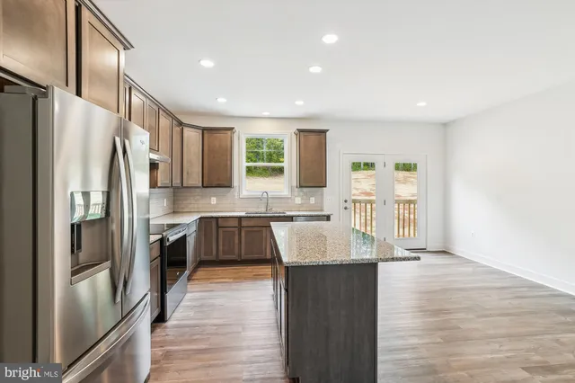 a kitchen with stainless steel appliances granite countertop a refrigerator a sink a stove and oven