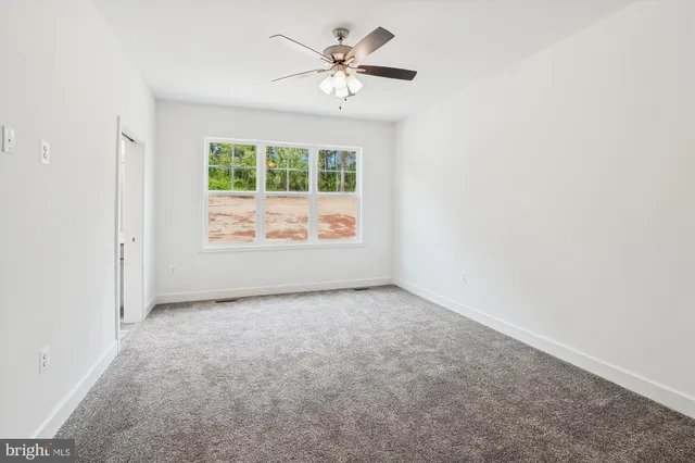 an empty room with closet and a ceiling fan