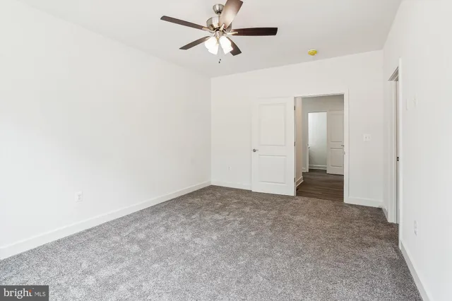 an empty room with closet and a ceiling fan