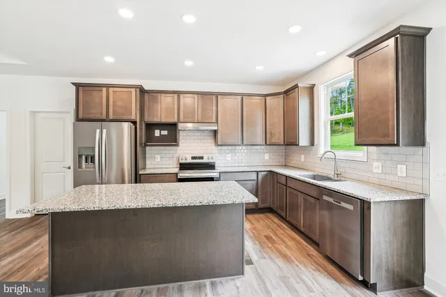 a large kitchen with kitchen island granite countertop a large window and stainless steel appliances