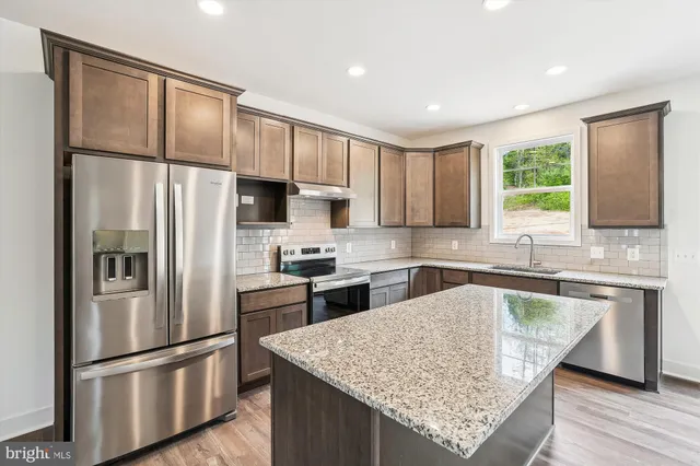 a kitchen with stainless steel appliances granite countertop a refrigerator sink and stove