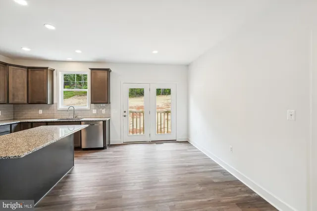 a large kitchen with cabinets wooden floor and a window