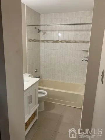 a bathroom with a granite countertop bathtub shower sink vanity and toilet