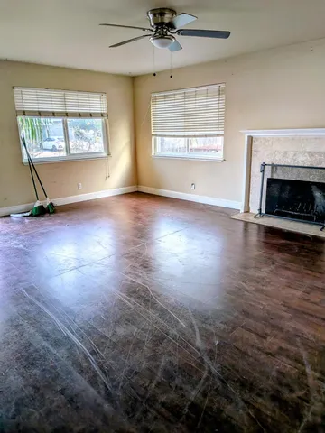 an empty room with wooden floor fireplace and windows