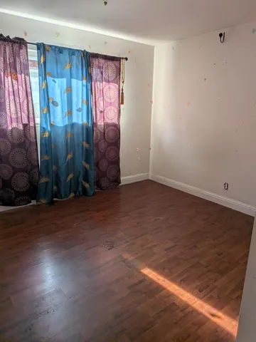 an empty room with wooden floor and window