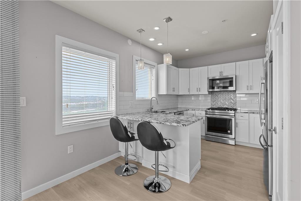 1825 Arcena Street, Unit 3 Pittsburgh, PA 15219 - Photo 11 of 31 a kitchen with kitchen island stainless steel appliances a stove a sink a microwave a refrigerator and cabinets