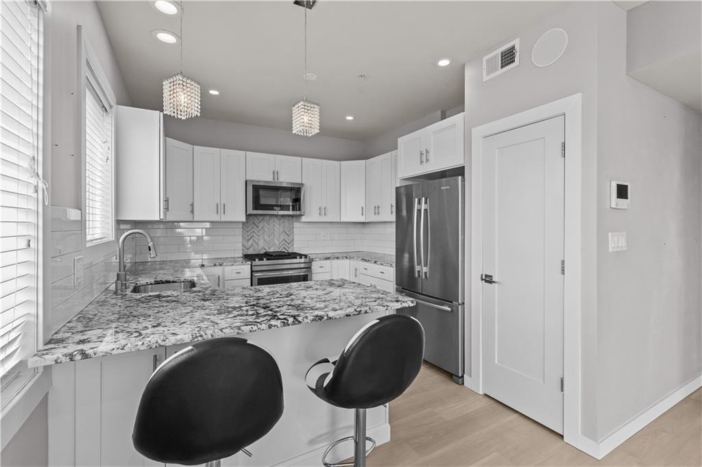 1825 Arcena Street, Unit 3 Pittsburgh, PA 15219 - Photo 9 of 31 a kitchen with kitchen island granite countertop a refrigerator a stove a sink and a microwave