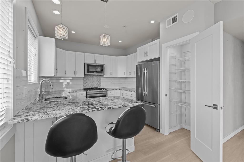 1825 Arcena Street, Unit 3 Pittsburgh, PA 15219 - Photo 10 of 31 a kitchen with stainless steel appliances granite countertop a refrigerator a sink a stove a microwave and island