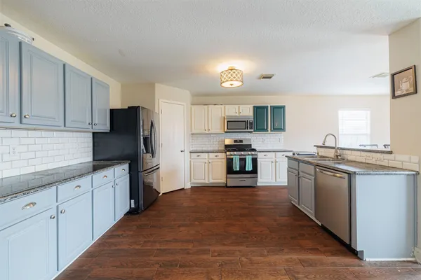 a kitchen with granite countertop a refrigerator stove top oven and sink