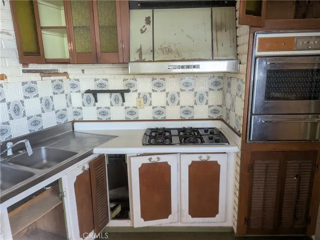 a kitchen with granite countertop a sink stove and cabinets