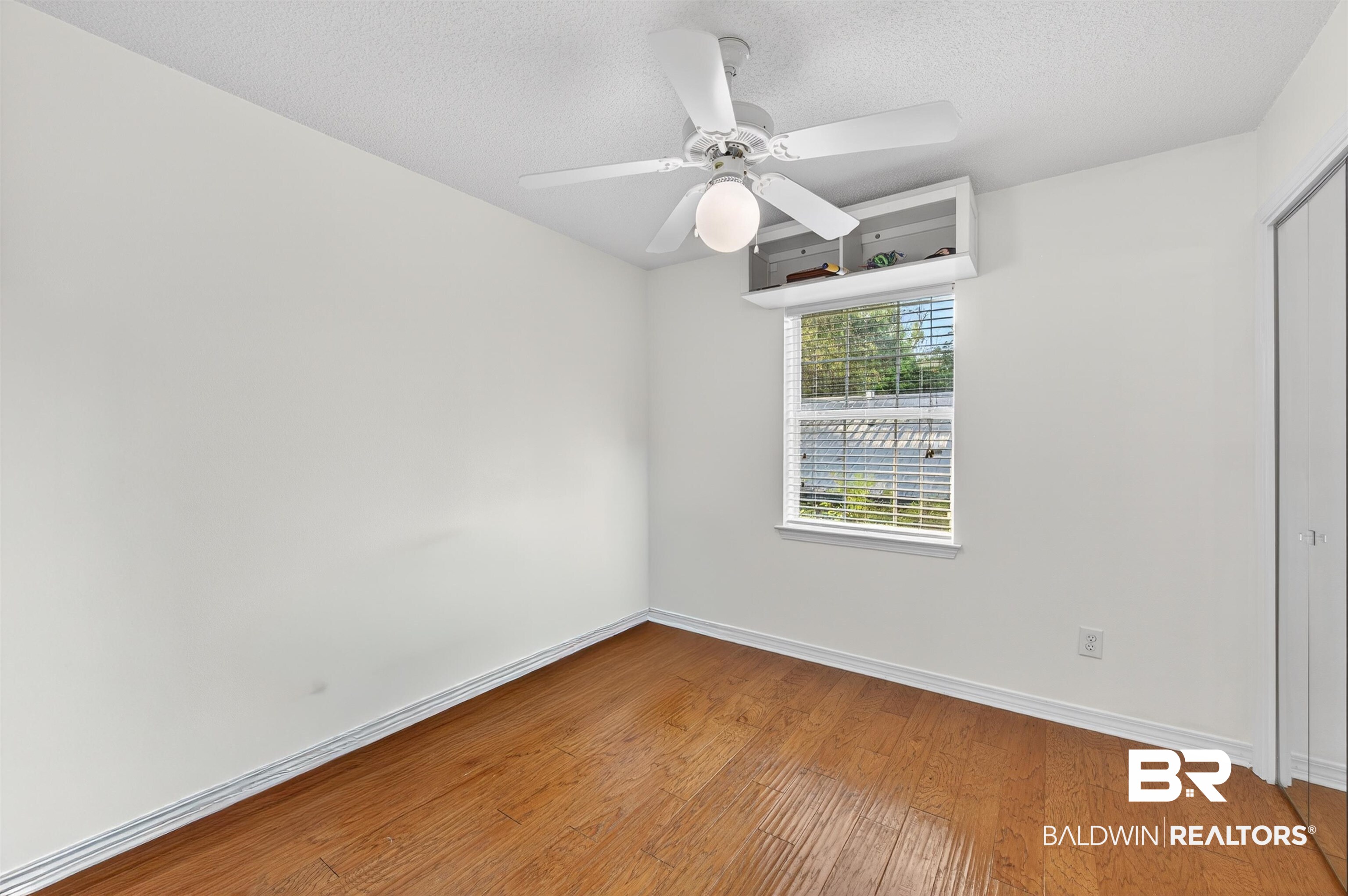 9624 North Bay Street Foley, AL 36535 - Photo 27 of 59 Room featuring wood-finish flooring, a ceiling fan with integrated lighting, a window with blinds, and built-in shelving above the window