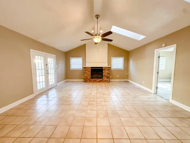 a view of an empty room with window and chandelier fan