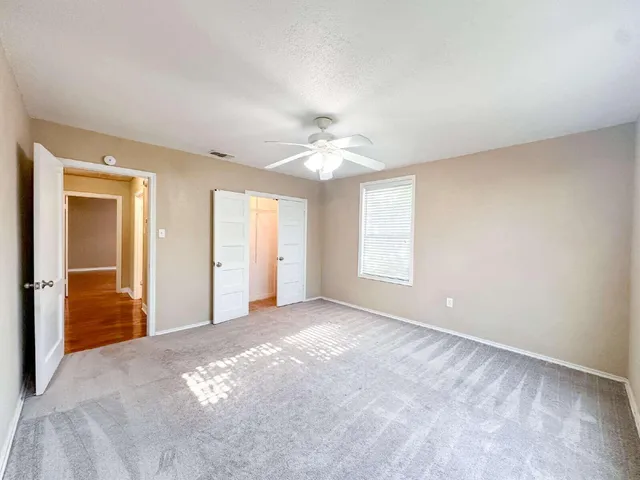 a view of a livingroom with a chandelier fan and windows