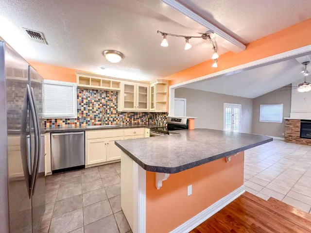 a kitchen with stainless steel appliances granite countertop a sink a stove and a refrigerator