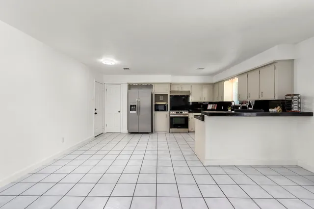 an empty room with wooden floor ceiling fan and windows