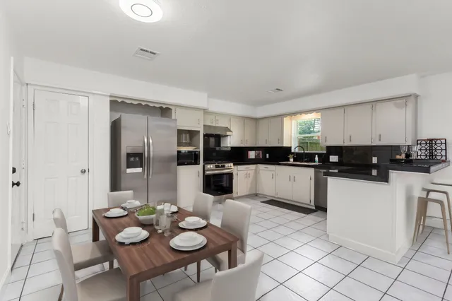 a kitchen with stainless steel appliances a refrigerator and white cabinets