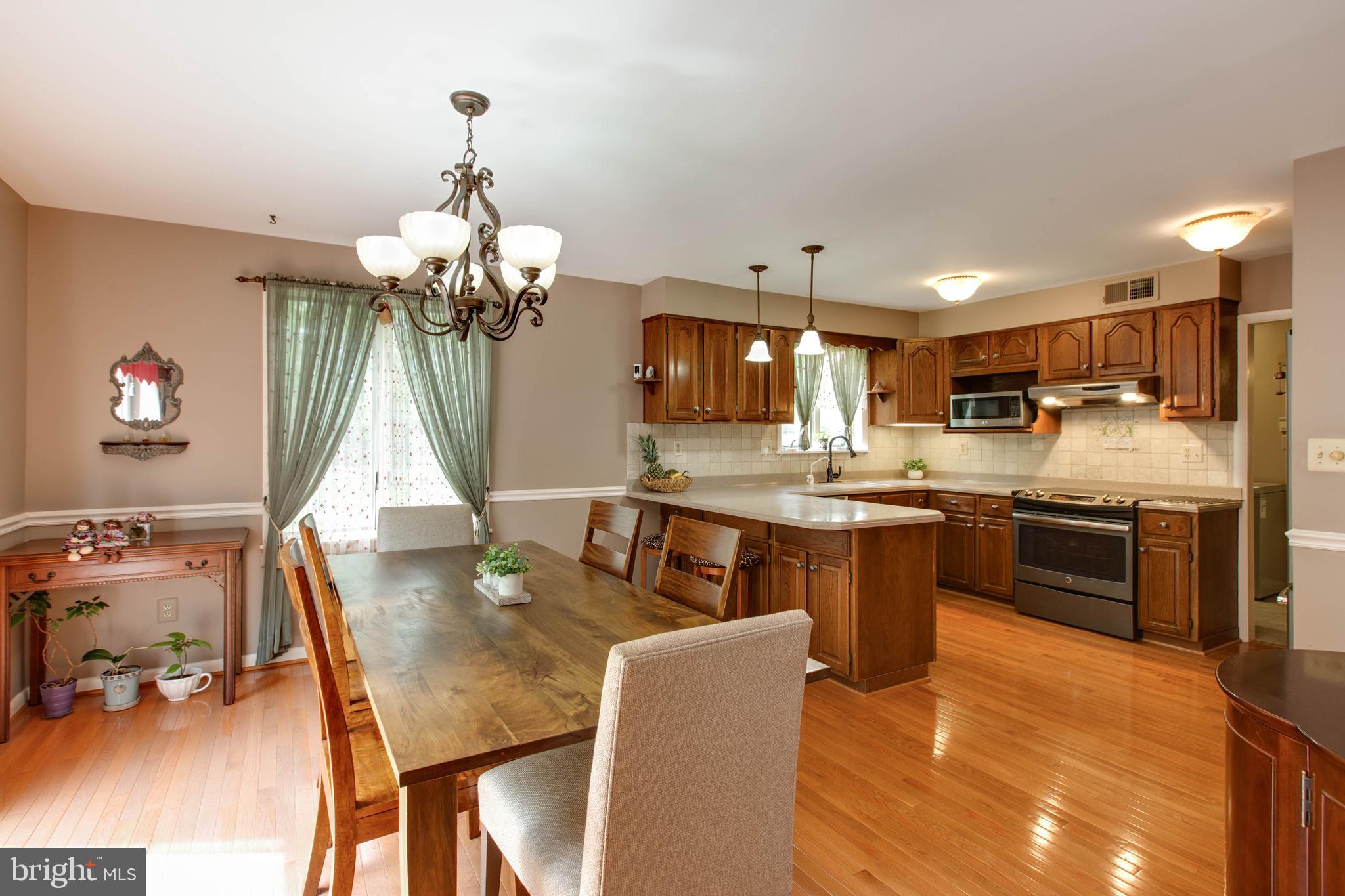 5519 Woodbine Road Sykesville, MD 21784 - Photo 18 of 69 a kitchen with stainless steel appliances granite countertop a stove top oven a sink dishwasher and a dining table with wooden floor