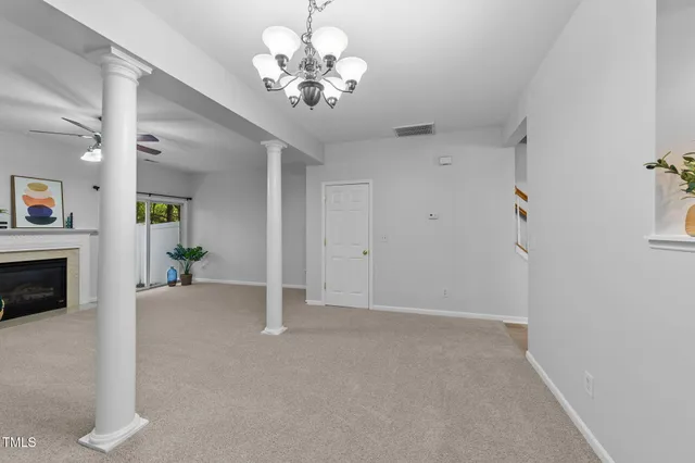 a view of a livingroom with a fireplace a chandelier fan and windows