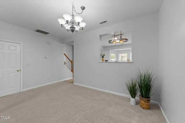 a view of a livingroom with a fireplace a chandelier and windows