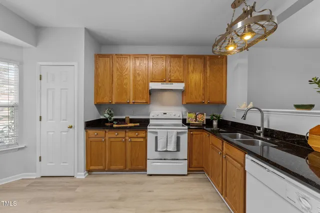 a kitchen with stainless steel appliances granite countertop a refrigerator a sink dishwasher a stove with wooden cabinets and floor