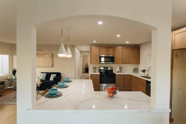 a kitchen with a sink stainless steel appliances and living room view