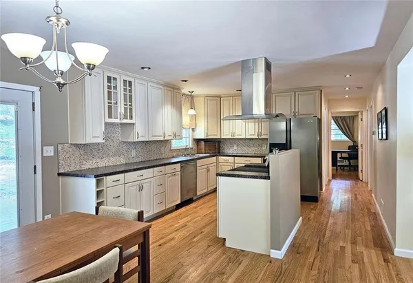 a kitchen with stainless steel appliances granite countertop a sink dishwasher a stove a dining table and chairs with wooden floor