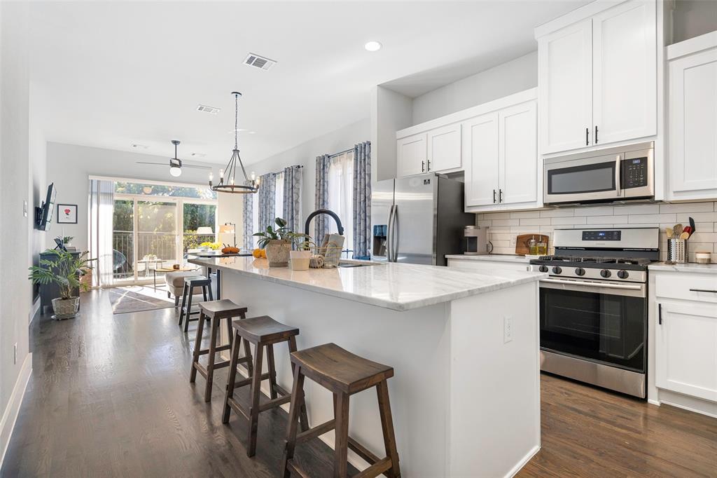 312 North Henderson Avenue, Unit 1 Dallas, TX 75214 - Photo 11 of 25 a kitchen with stainless steel appliances a table chairs refrigerator and cabinets