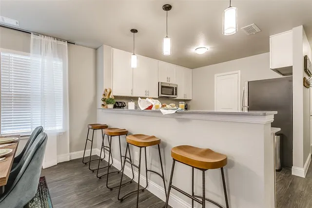 a kitchen with stainless steel appliances granite countertop a sink a stove a refrigerator cabinets and chairs