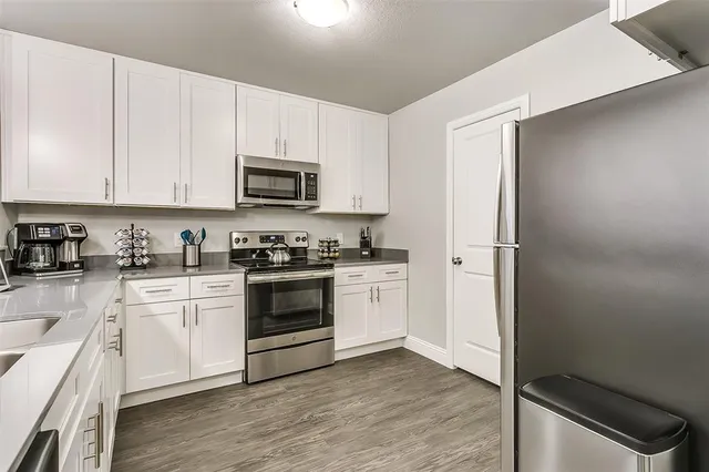 a kitchen with stainless steel appliances white cabinets and a stove top oven