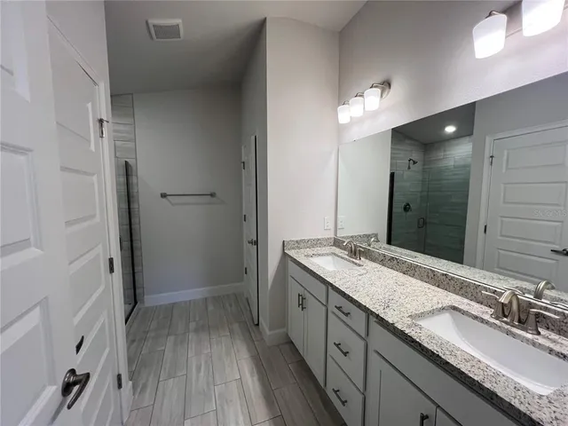 a bathroom with a granite countertop sink a mirror and a shower