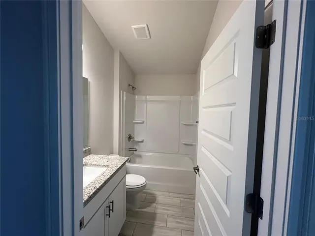 a bathroom with a granite countertop sink a toilet and shower