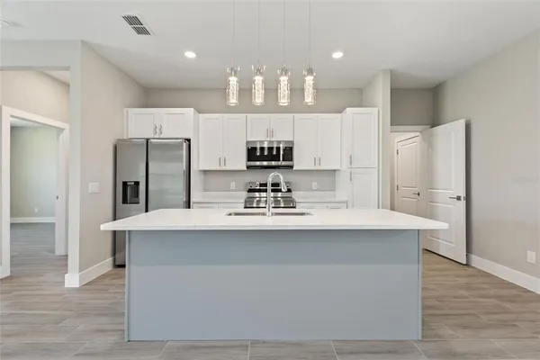 a view of a kitchen with kitchen island a sink stainless steel appliances and cabinets