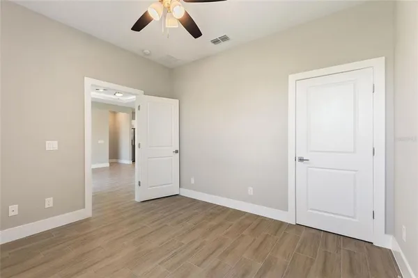 an empty room with wooden floor and a ceiling fan