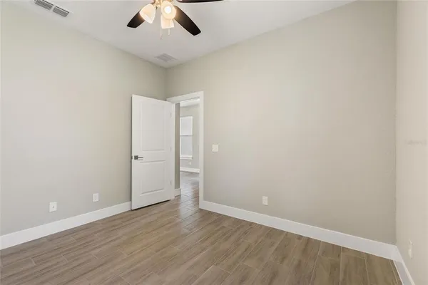 an empty room with a ceiling fan and wooden floor